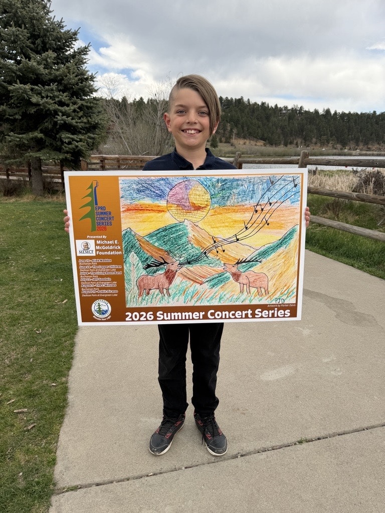 A smiling child holds a colorful poster for the 2026 Summer Concert Series, featuring a scenic drawing with wildlife.