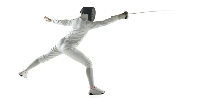 A fencer in a lunge pose with a foil, wearing protective gear on a white background.