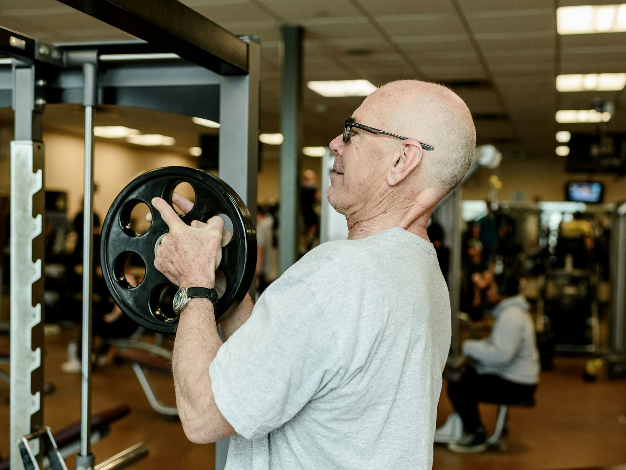 A man at the gym holding a weight plate.