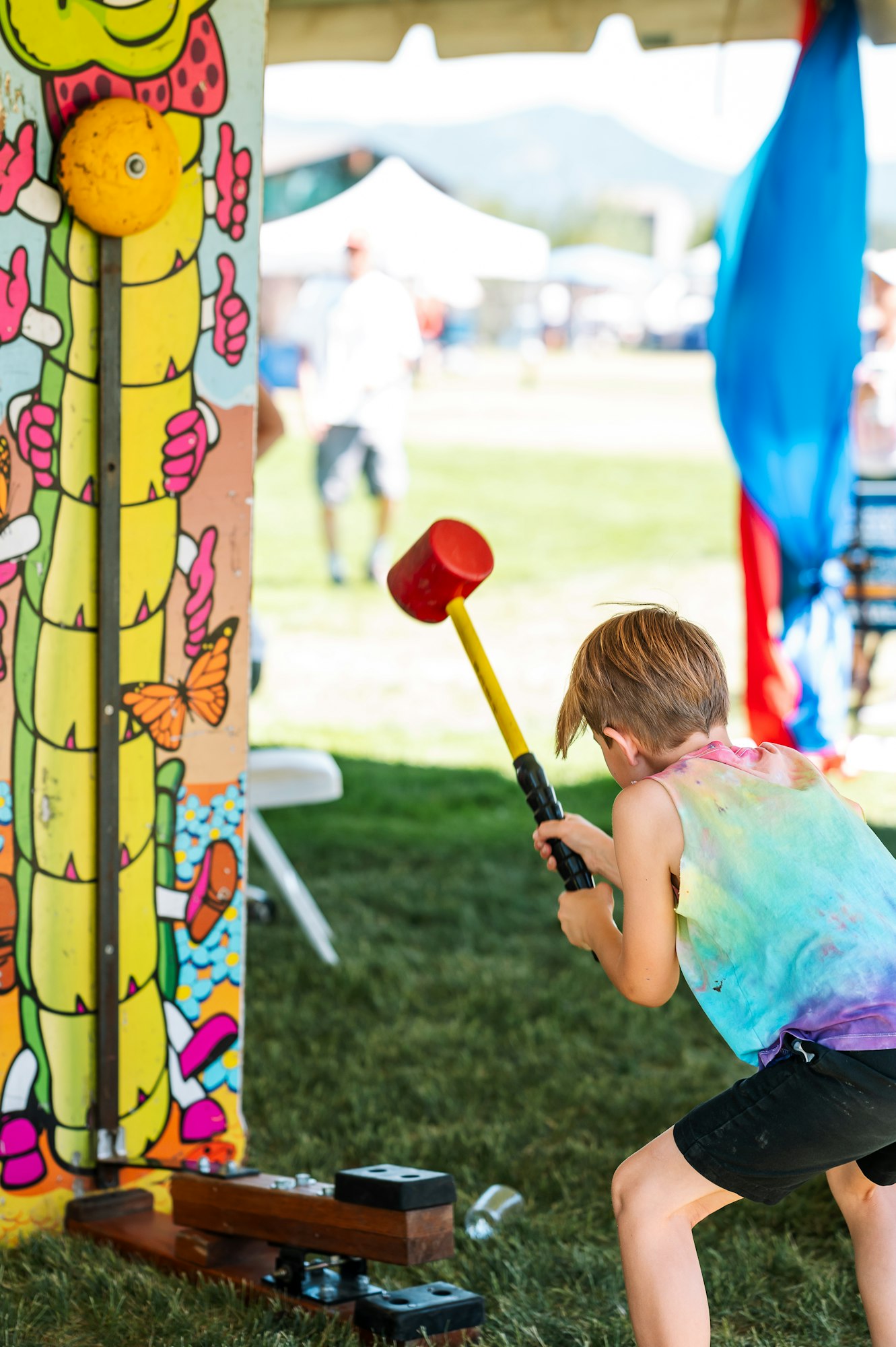 Child striking carnival strength tester with a mallet.