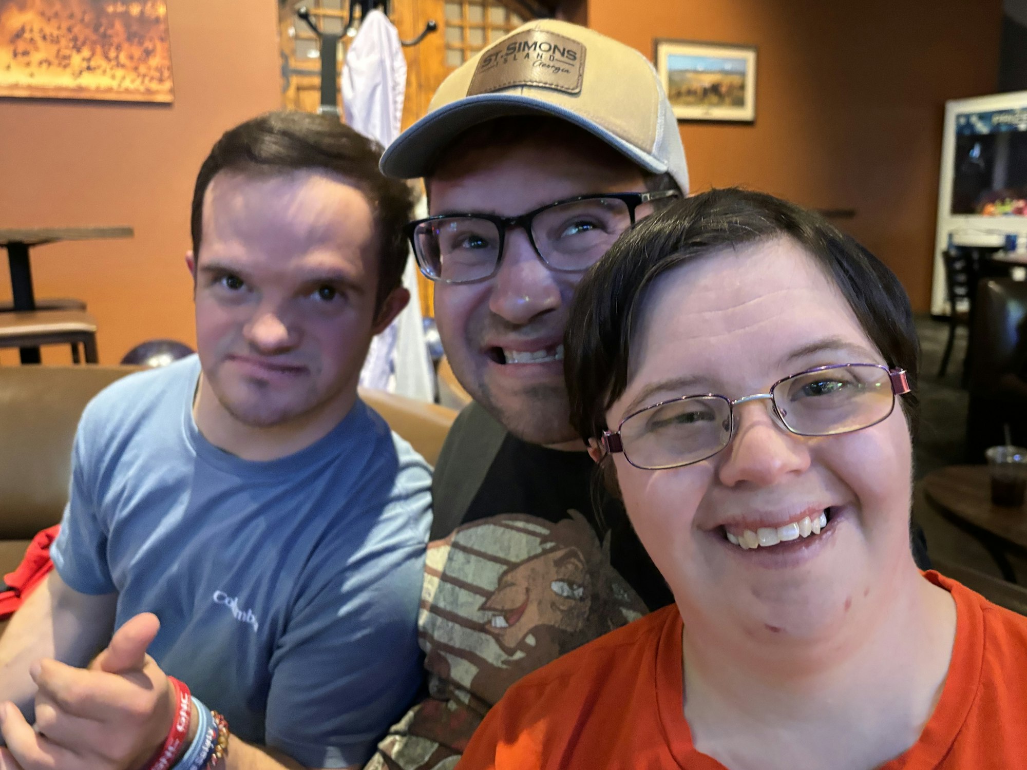 Three smiling friends enjoying time together indoors, sitting on a couch with a casual backdrop.