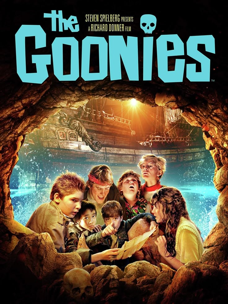 Poster for "The Goonies" with a group of kids in a cave, holding a map, with a ship and skulls in the background.