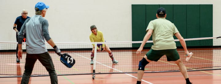 Four people playing pickleball indoors.