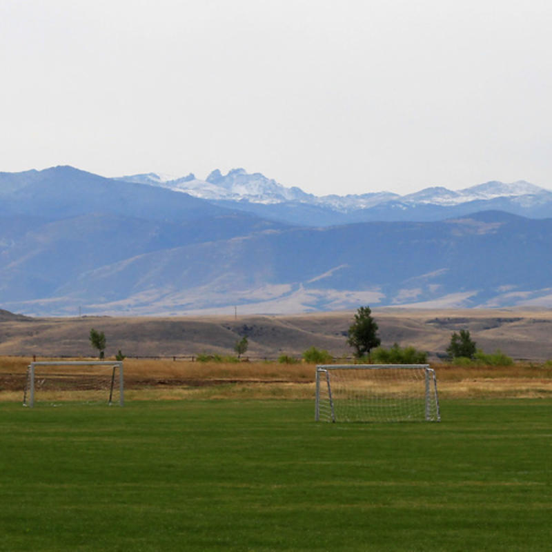 Photo of soccer goals in a field with mountains in the background
