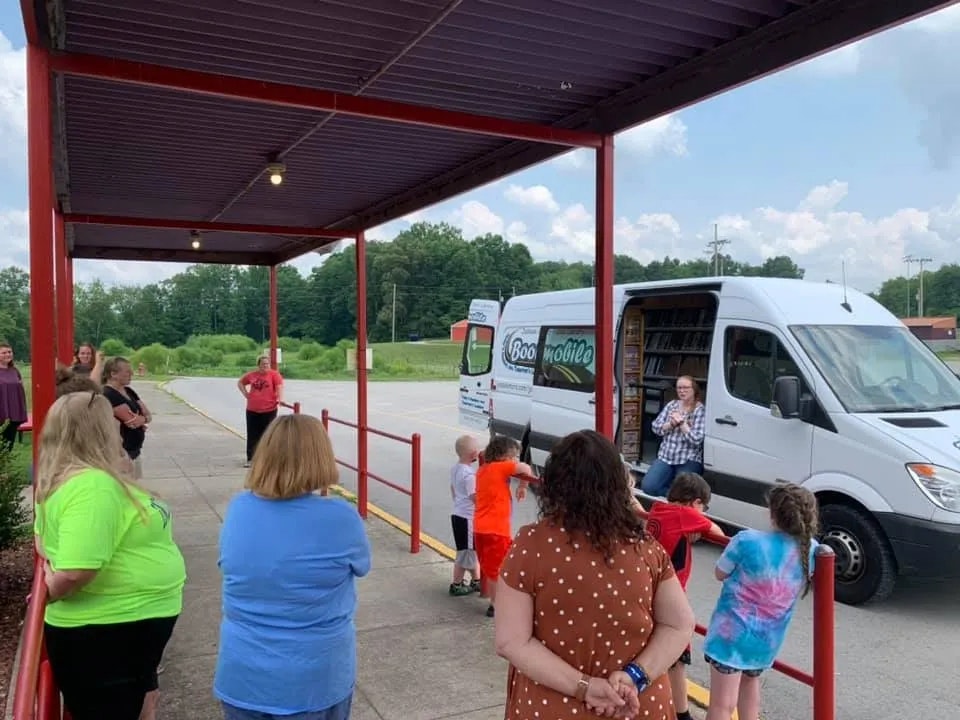 People gathered around a "Bookmobile" van at a community event.