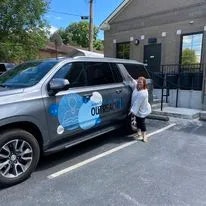 A child mimics a pose next to an SUV with a water cooler advertisement.