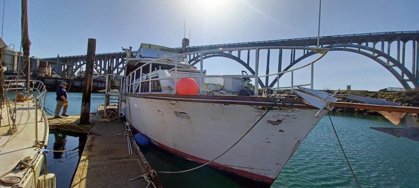 A person near a docked boat with a bridge in the background.