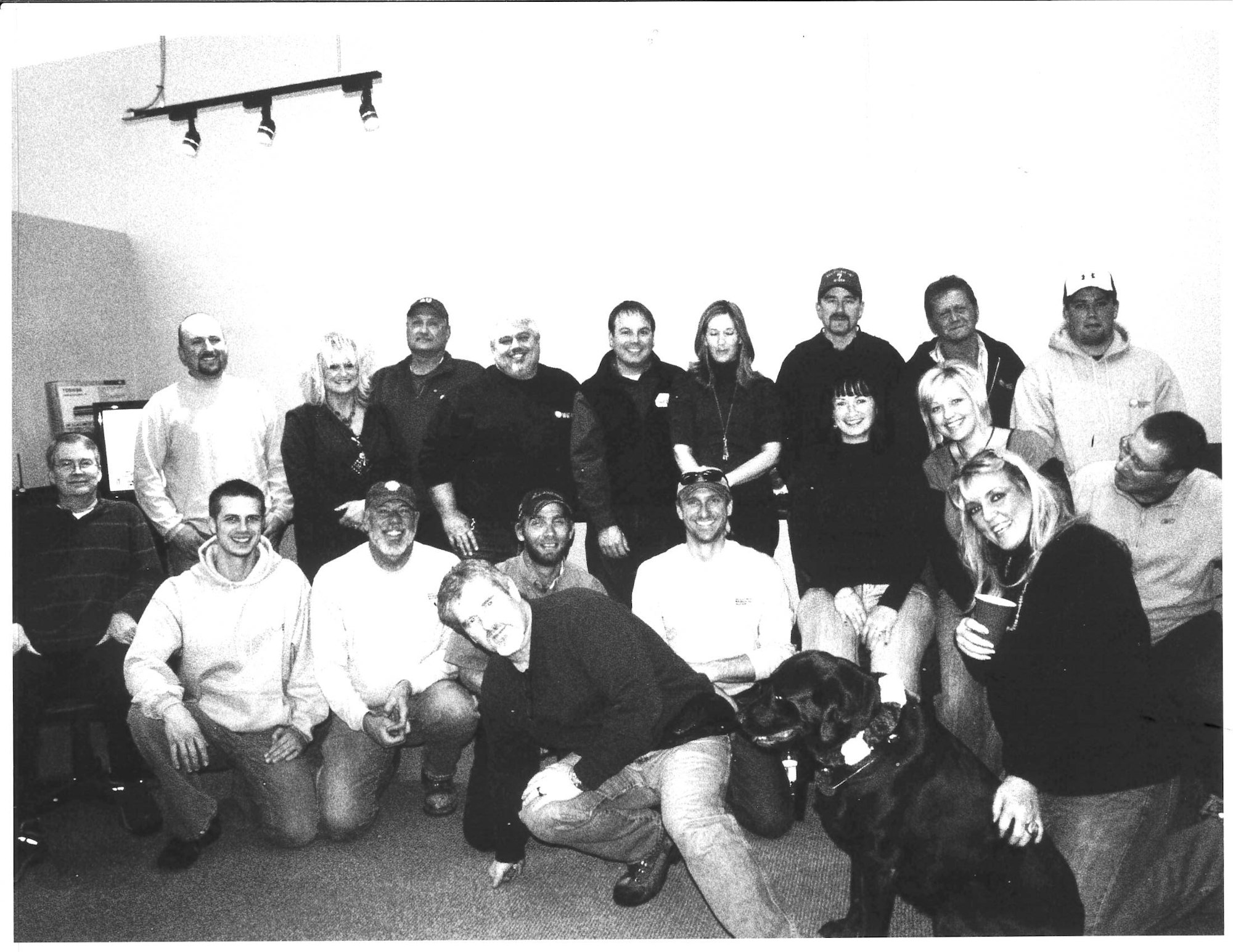 A group of people posed together indoors, including a dog in the front.