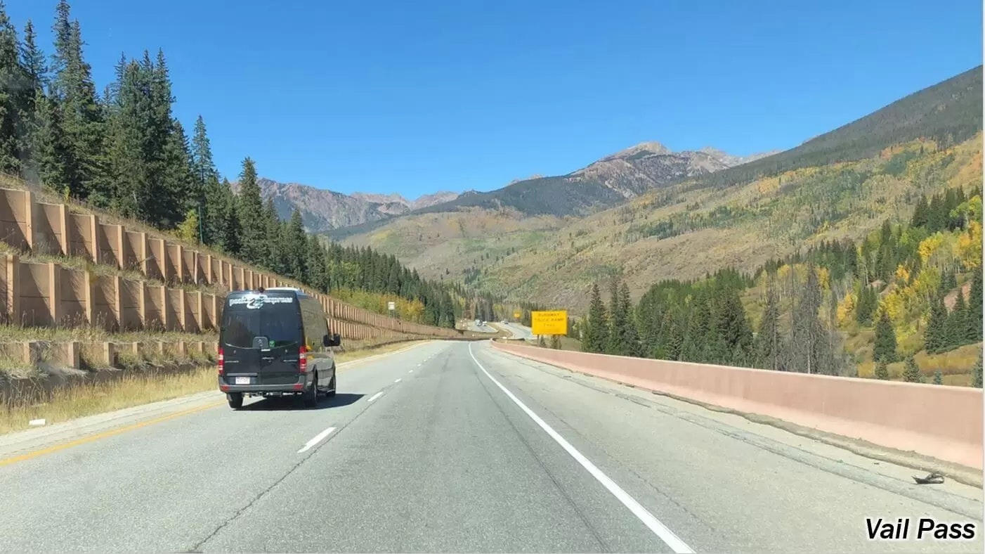 A vehicle on a highway with mountain scenery and text "Vail Pass."