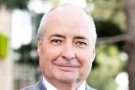 Close-up of a smiling, bald man with a suit.
