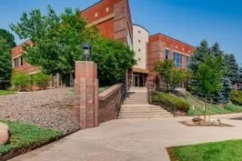 Modern building, clear sky, lush greenery, and a paved pathway.