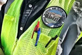 A safety vest with pens and a badge reading "Drainage and Flood Control Division"