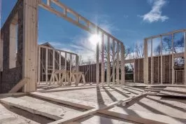 Wooden frame of a house under construction with clear blue sky in the background.