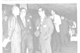 A black and white photo showing people in conversation, likely at a social or professional gathering.