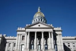 A neoclassical building with a dome, likely a capitol or government structure, under a clear blue sky.