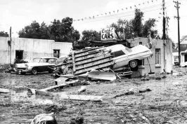 Flood aftermath with damaged cars and debris.