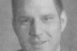 Black and white photo of a smiling man with blurred features.