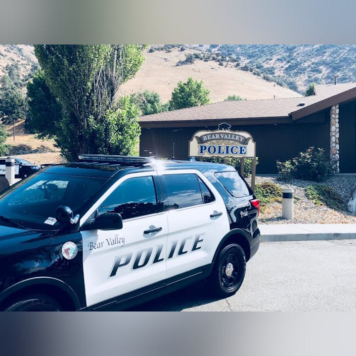 Police SUV parked in front of Bear Valley Police station with mountains in the background.