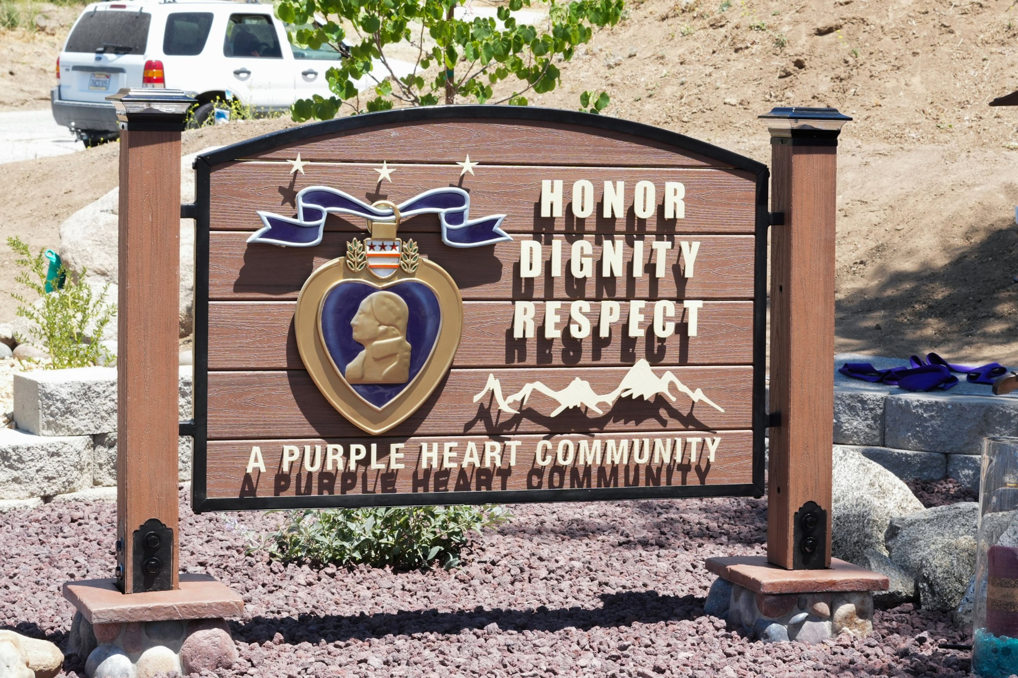 Sign with a Purple Heart medal design, text "Honor Dignity Respect," and "A Purple Heart Community" below.