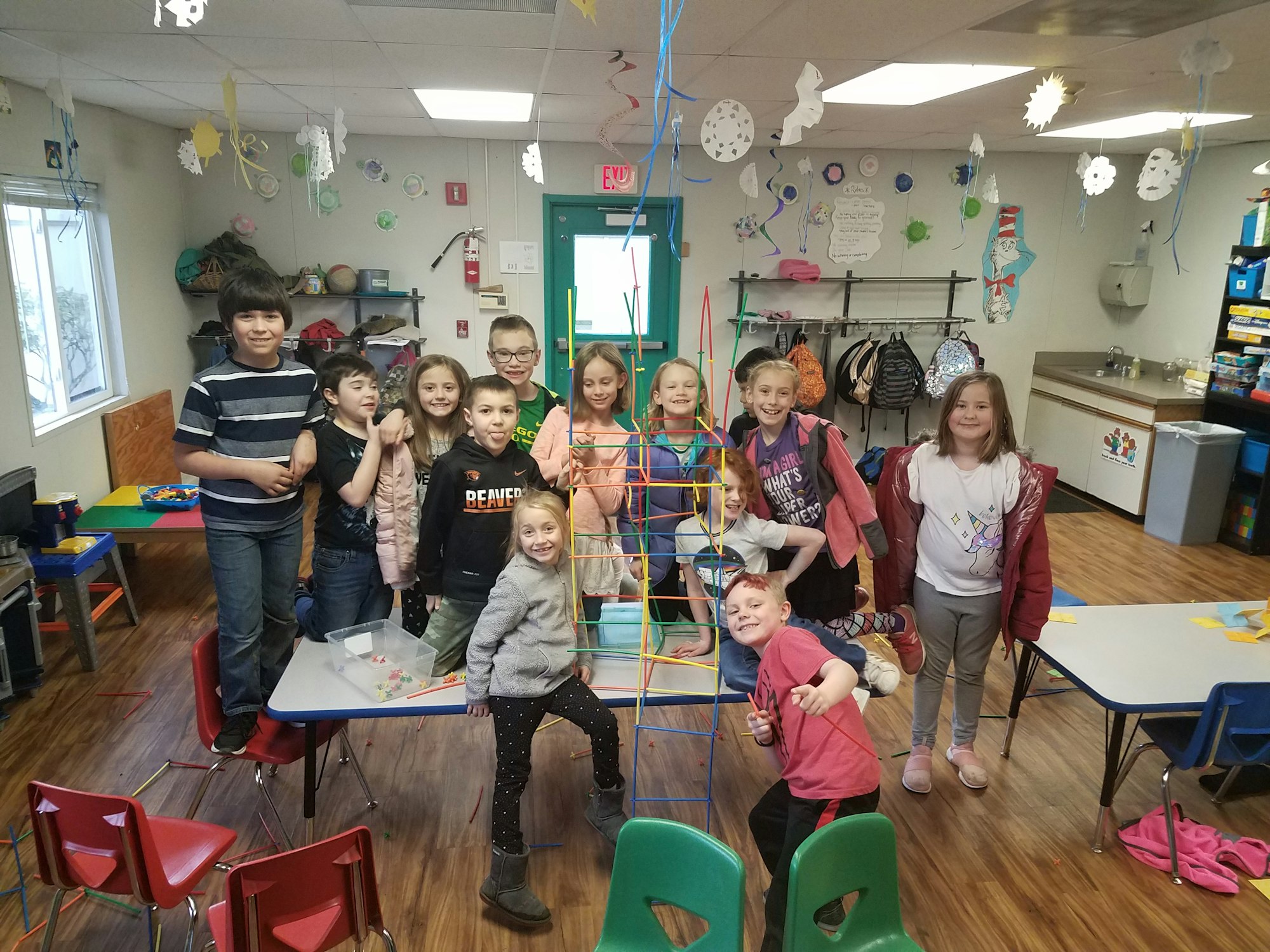 Group of children posing with a colorful tower structure in a classroom.