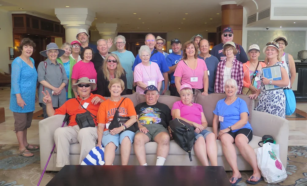 Group of smiling people posing in a lobby, likely tourists or friends.
