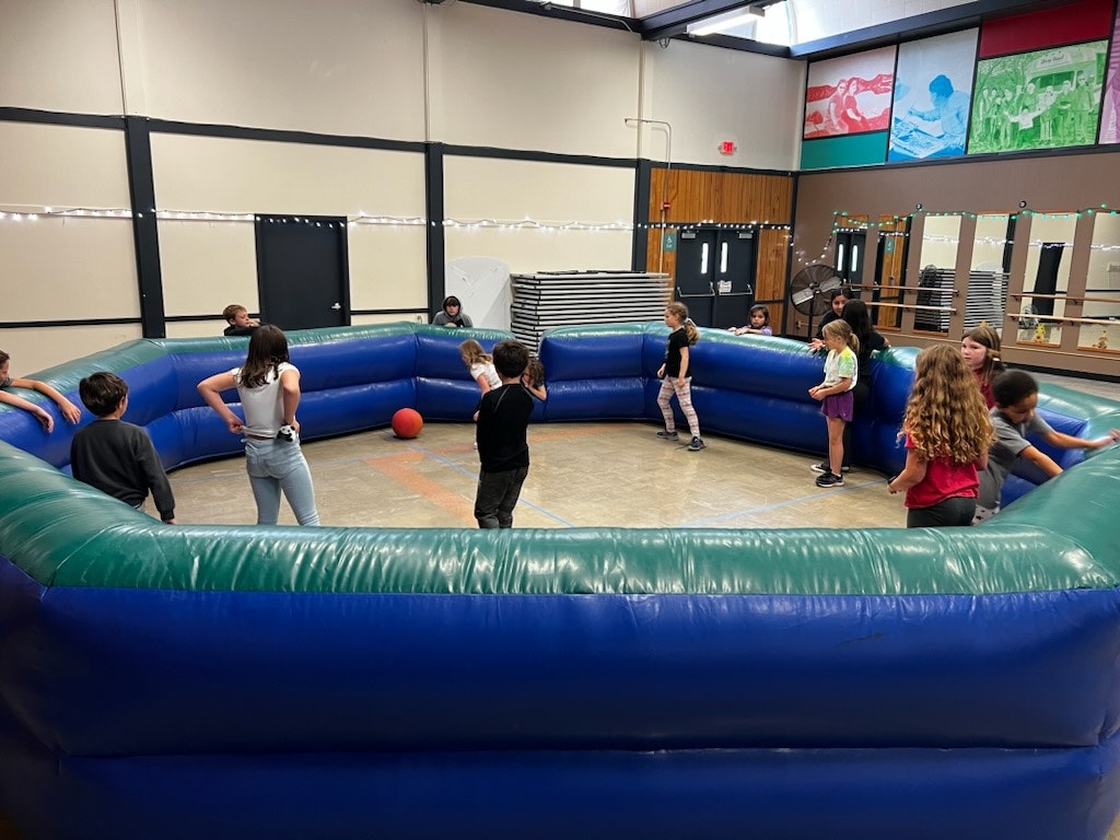 Children playing a ball game in an inflatable arena.