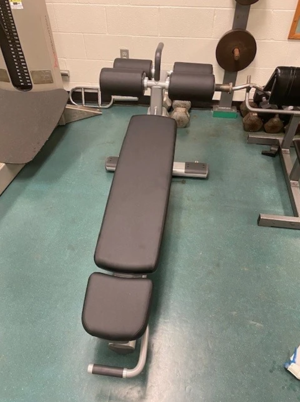 A gym with a workout bench, weights, and equipment.