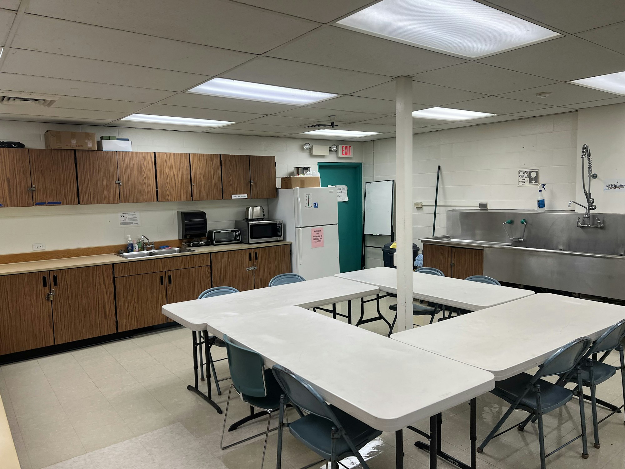 A break room or kitchen area with tables, chairs, cabinets, appliances, and a large sink.