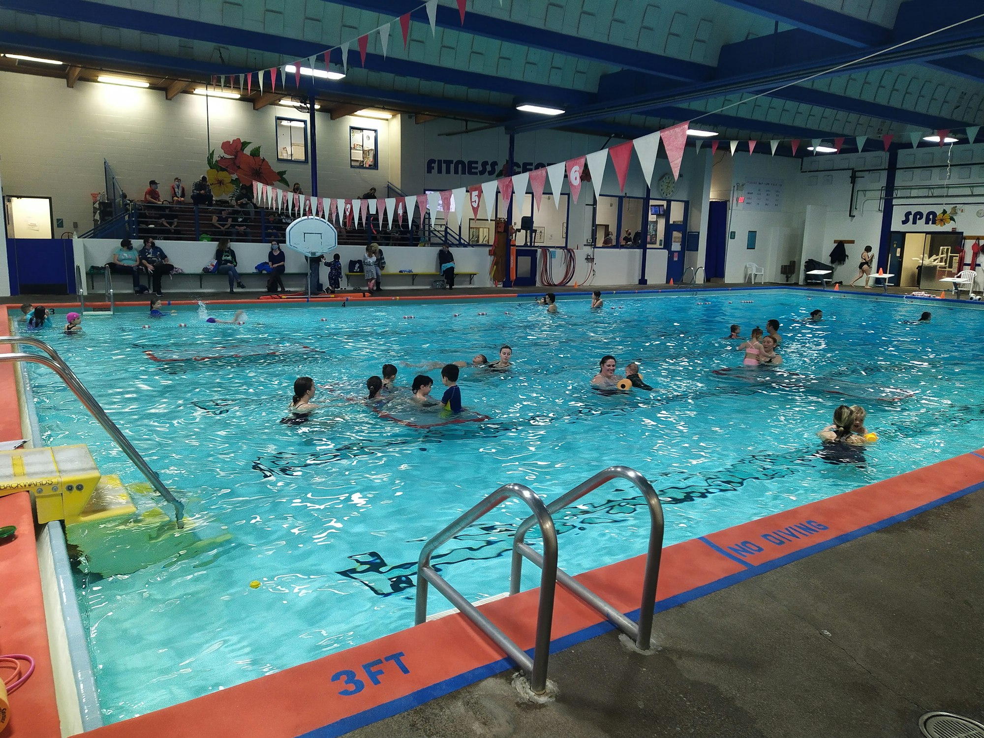 An inverted image of a swimming pool with swimmers and a diving platform.