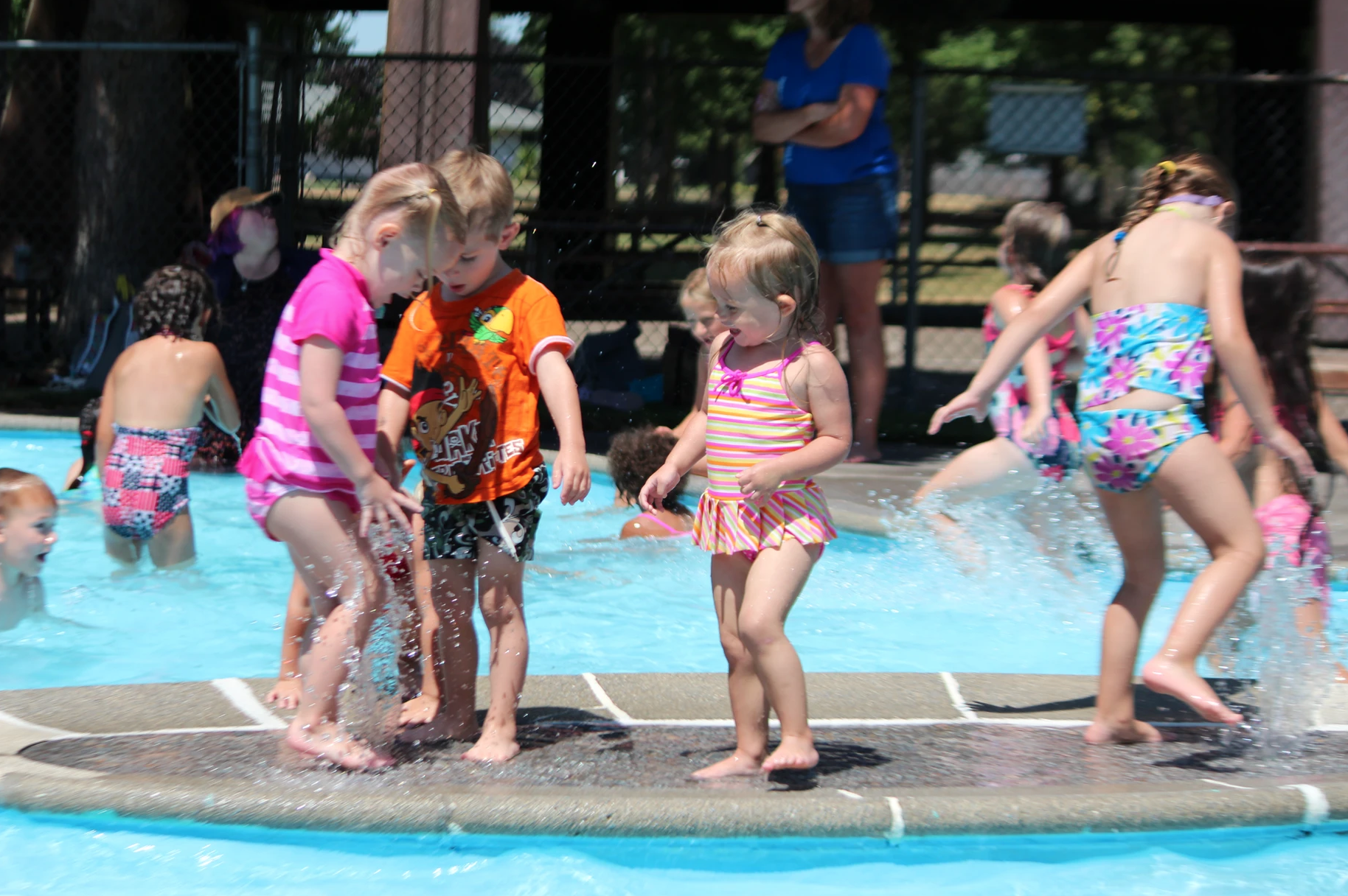 Children playing in a splash pad on a sunny day.