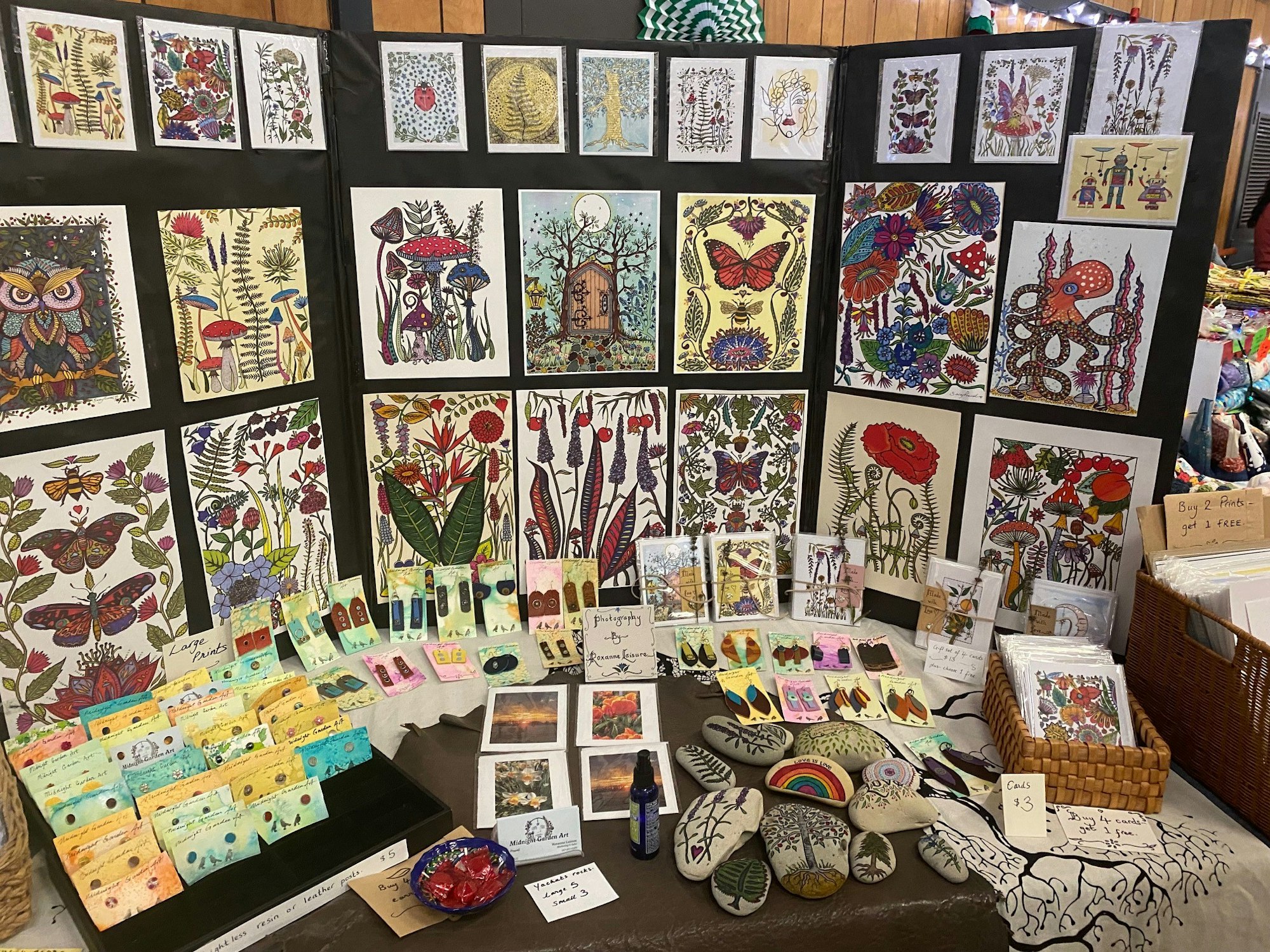 Art booth with prints, bookmarks, paintings, and crafts on display.