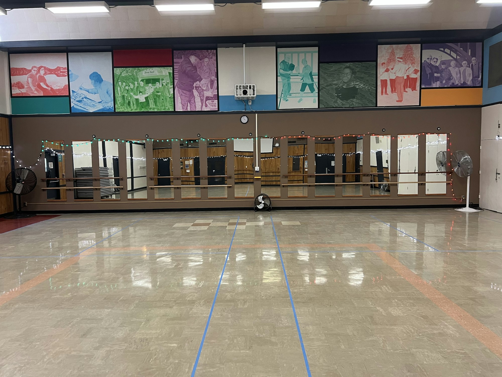 A dance studio with mirrors, wall art, fans, and lights.