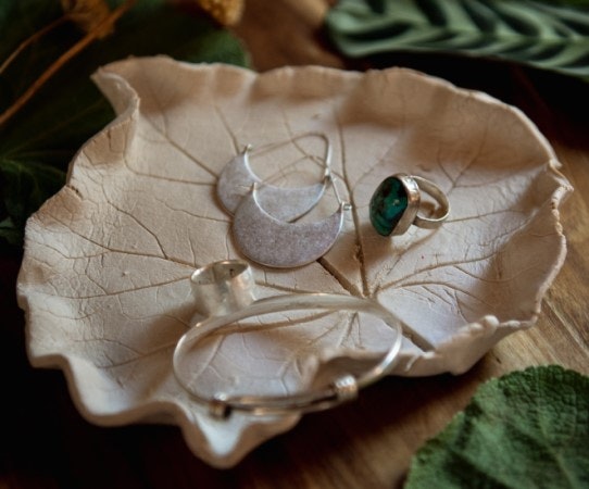 Jewelry displayed on a leaf-shaped dish; includes a ring and two bracelets.