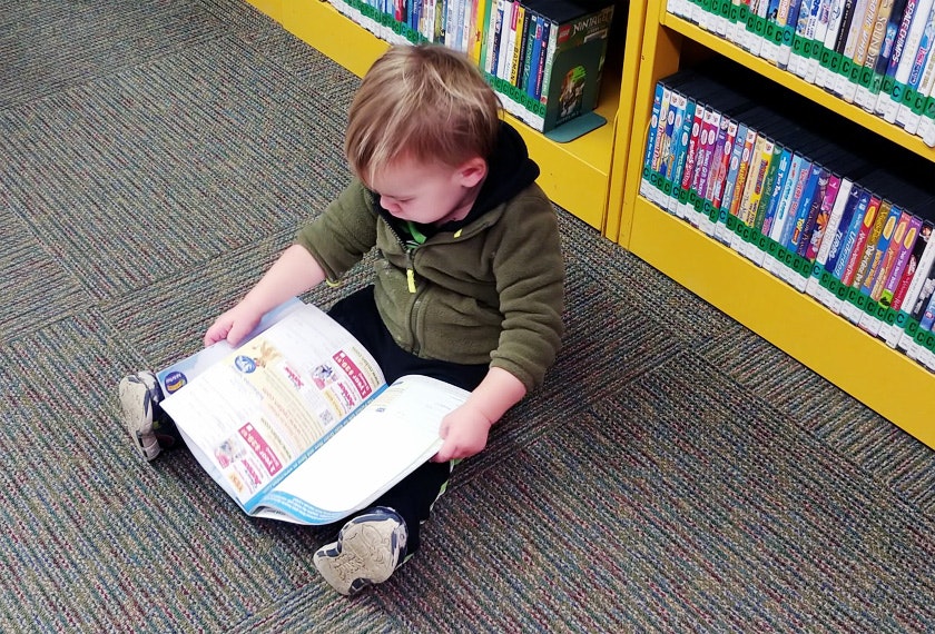May contain: person, reading, book, publication, indoors, library, boy, child, and male