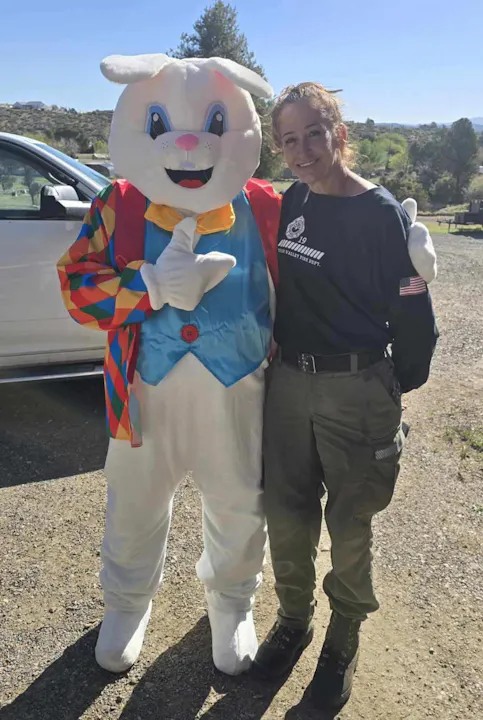 A person poses with a giant bunny mascot in a festive outdoor setting.