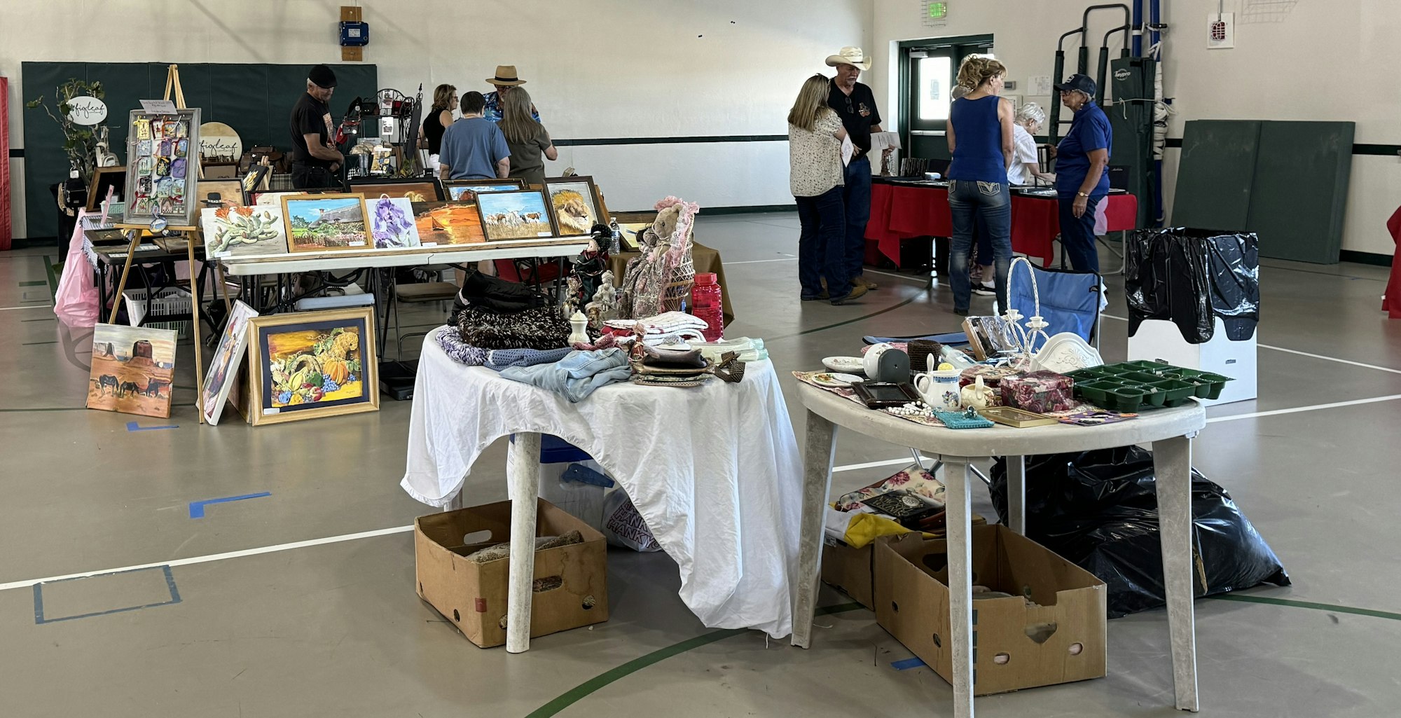 Indoor market with art, vintage items, and people browsing.