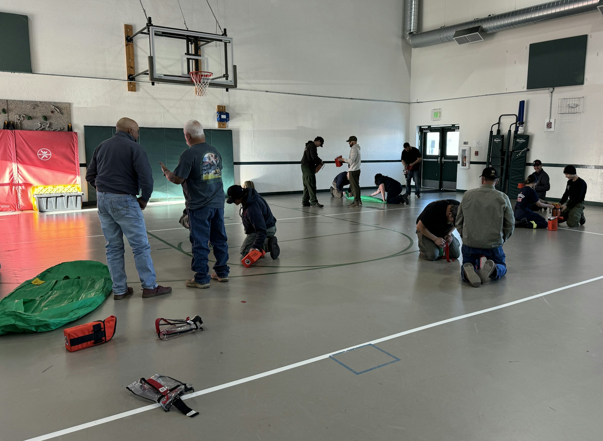 People in a gym practicing CPR with dummies and training equipment on the floor.