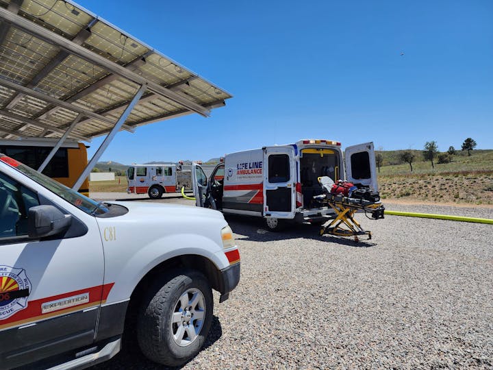 Emergency vehicles and a stretcher outside under a clear sky.