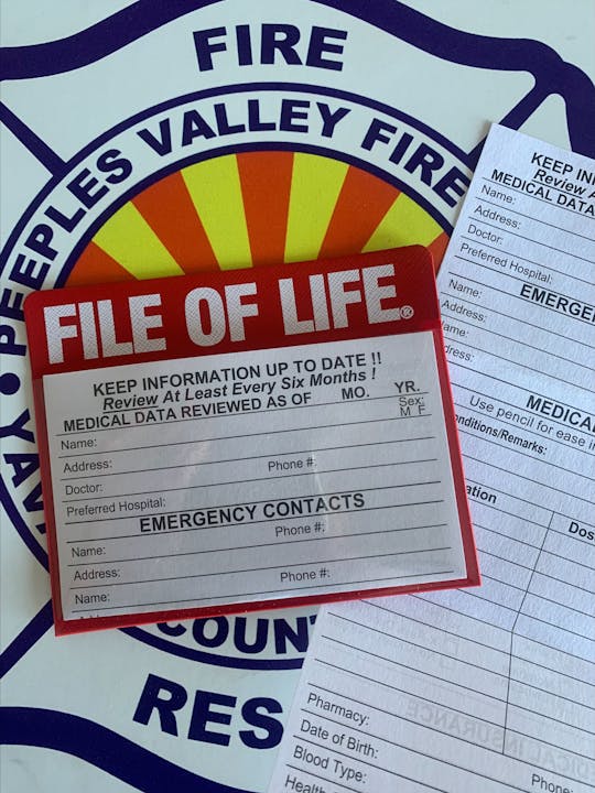 A "File of Life" card with medical information and emergency contacts, against a background of the People's Valley Fire Department logo.