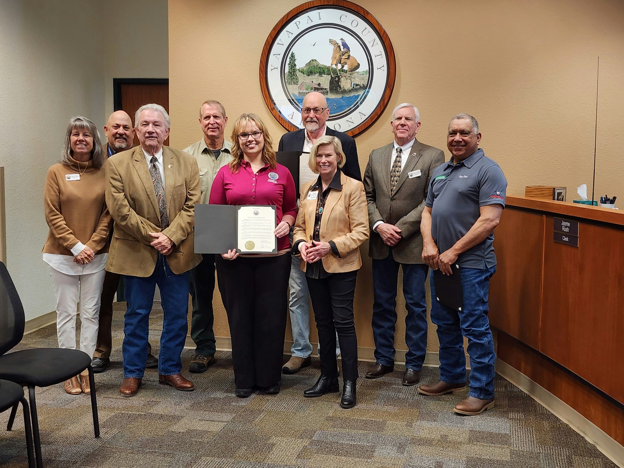 Group of people posing with a certificate in front of a seal that reads "Yavapai County Arizona."