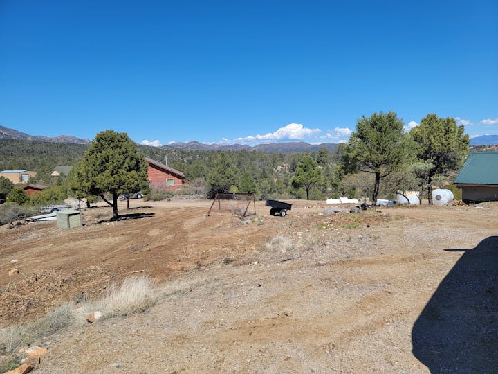 Rural landscape with buildings, trees, clear sky, and mountain background.