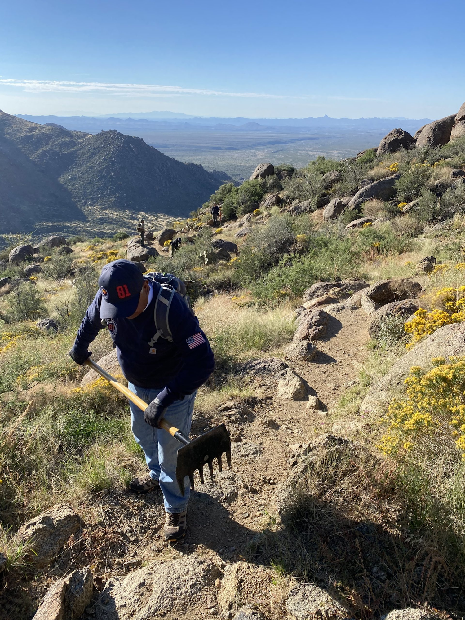 May contain: nature, outdoors, wilderness, rock, adventure, hiking, leisure activities, person, soil, plant, vegetation, clothing, glove, grass, bag, device, shovel, tool, face, head, photography, portrait, backpack, path, and landscape