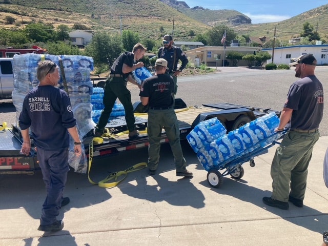 Firefighters loading bottled water onto a truck.
