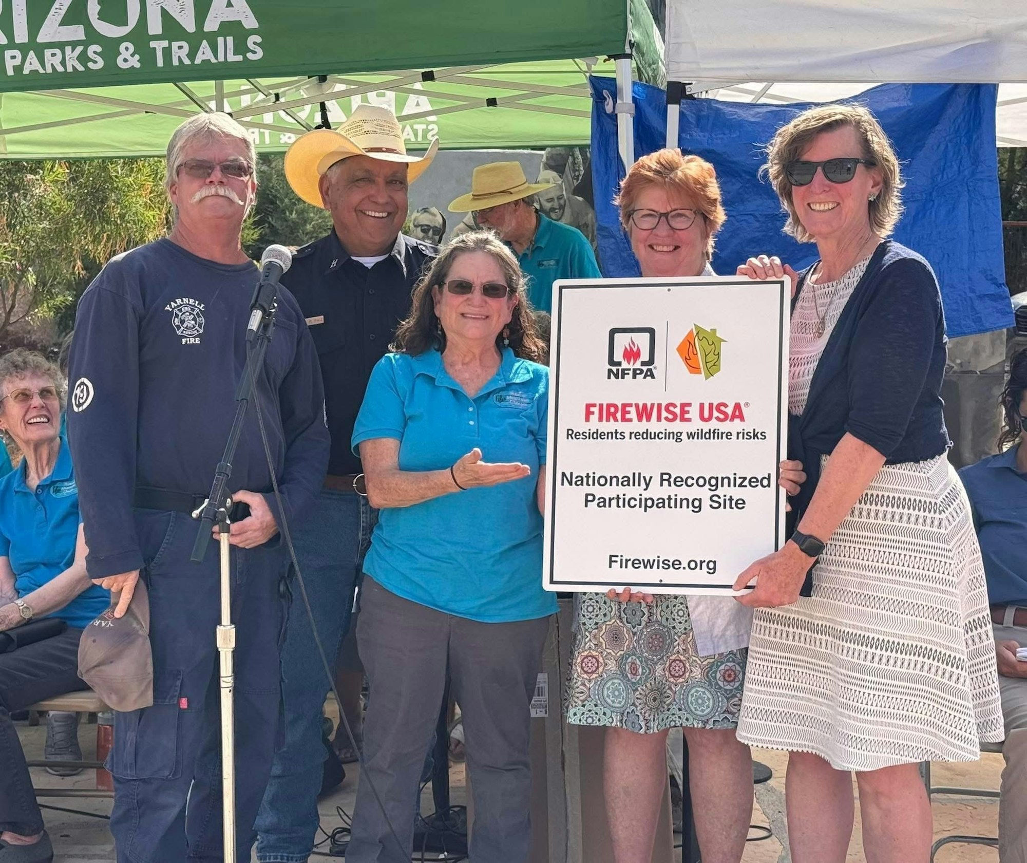 Group holding a "Firewise USA" sign, celebrating wildfire risk reduction.