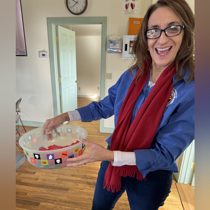 A smiling woman holding a bowl with Halloween decorations.