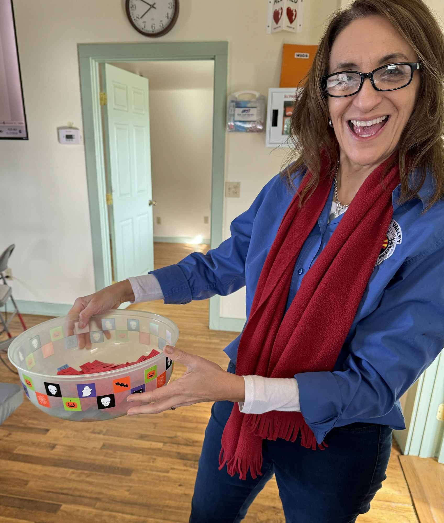 A smiling woman holding a bowl with Halloween decorations.
