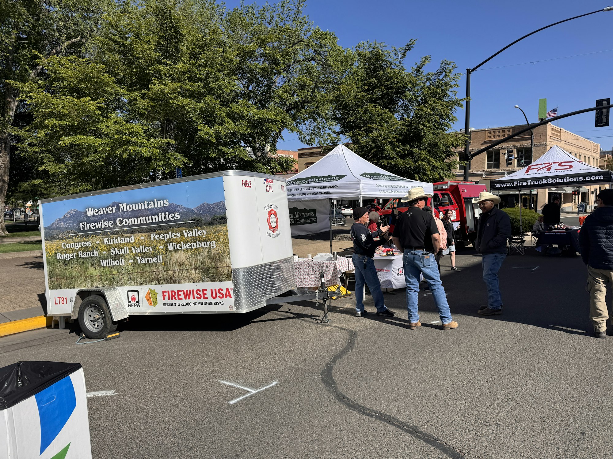 A gathering for fire safety awareness, featuring a trailer promoting firewise communities and several booths set up for information.