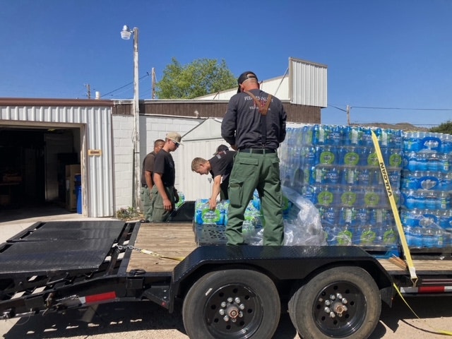 People unloading water bottle pallets from a trailer.