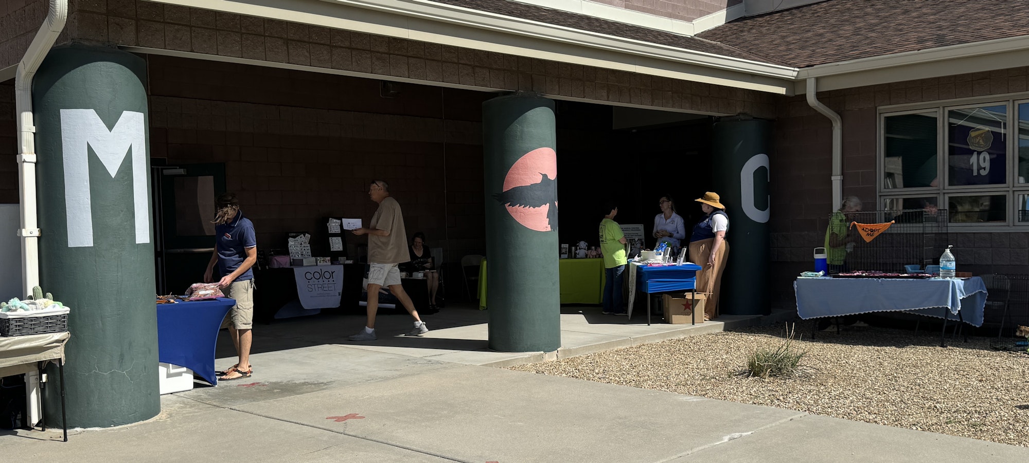 Outdoor event with tables, people, and a column with a shark graphic.