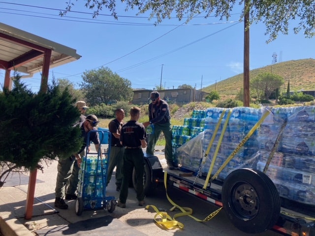 People unloading water bottles from a trailer.